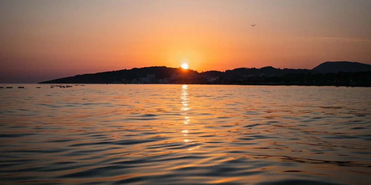 Capture of a serene sunset over Ulcinj beach, Montenegro, reflecting vibrant colors on the water.