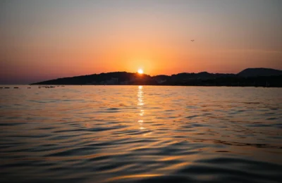 Capture of a serene sunset over Ulcinj beach, Montenegro, reflecting vibrant colors on the water.