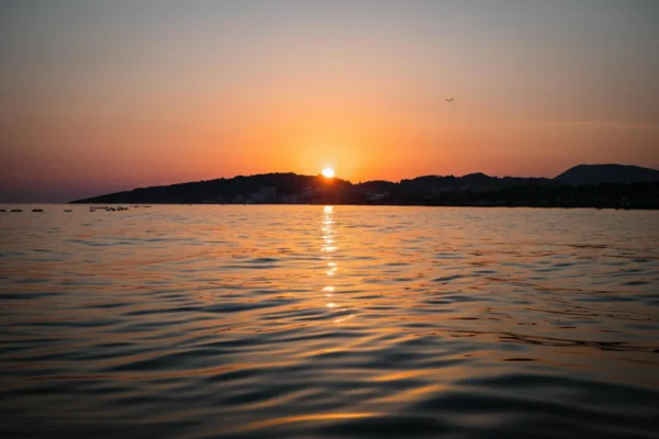 Capture of a serene sunset over Ulcinj beach, Montenegro, reflecting vibrant colors on the water.