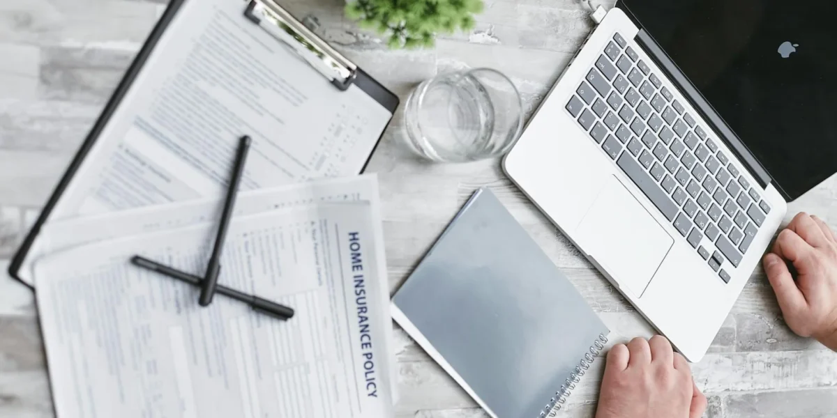 Top view of home insurance forms, laptop, and documents on a desk, conveying a professional office setting.