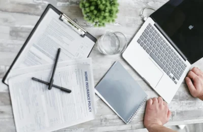 Top view of home insurance forms, laptop, and documents on a desk, conveying a professional office setting.