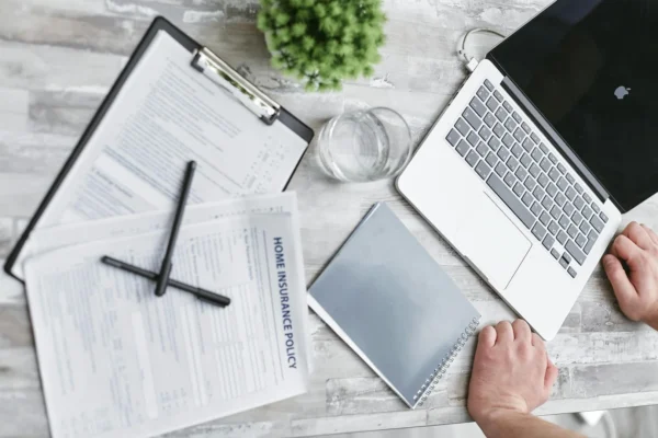 Top view of home insurance forms, laptop, and documents on a desk, conveying a professional office setting.