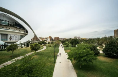 A spacious urban park with modern architecture and green walkways under a cloudy sky.