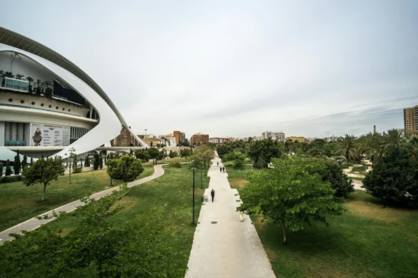 A spacious urban park with modern architecture and green walkways under a cloudy sky.