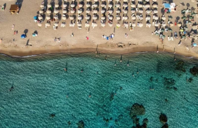 Aerial view of Chania beach, Greece with umbrellas and turquoise water.