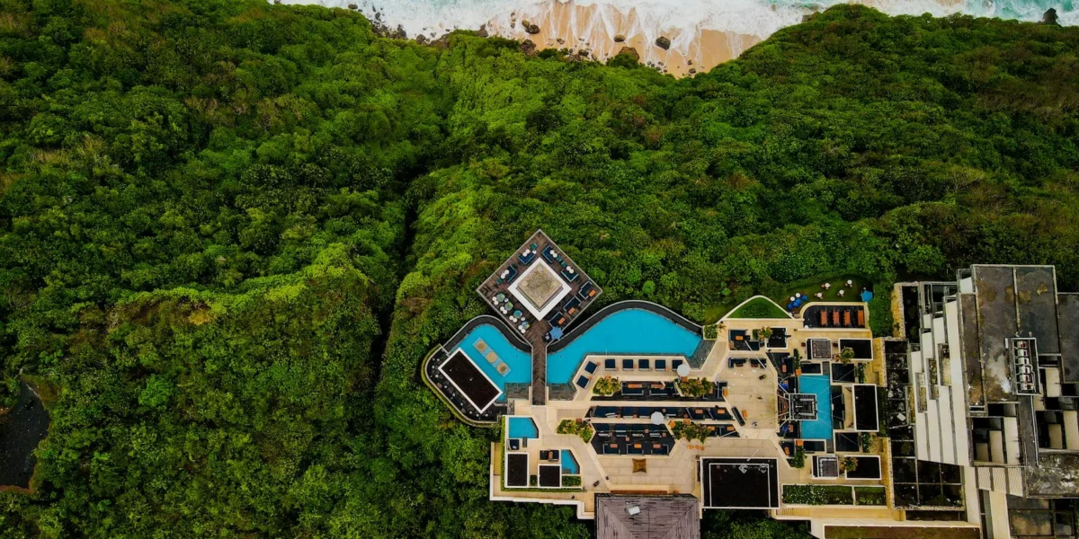 Stunning aerial shot of a luxury resort in Bali, surrounded by lush greenery and ocean view.