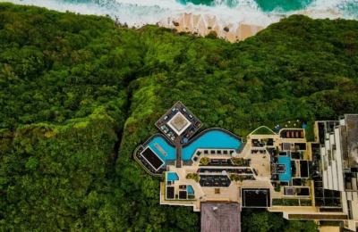 Stunning aerial shot of a luxury resort in Bali, surrounded by lush greenery and ocean view.