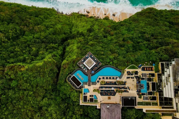 Stunning aerial shot of a luxury resort in Bali, surrounded by lush greenery and ocean view.
