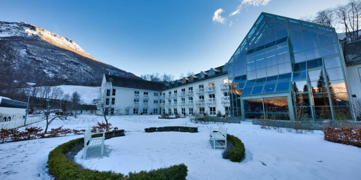 A modern hotel nestled in a snowy valley surrounded by mountains in Norway.