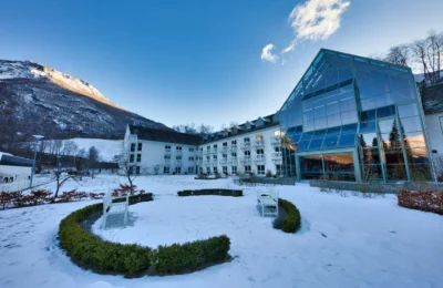 A modern hotel nestled in a snowy valley surrounded by mountains in Norway.