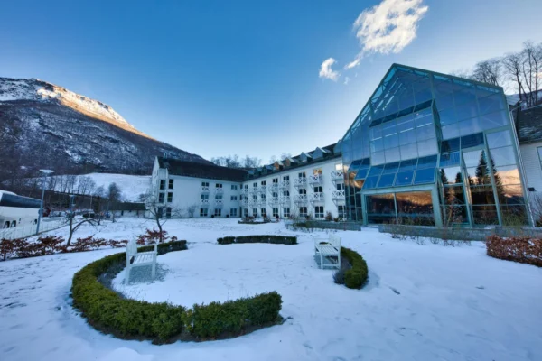 A modern hotel nestled in a snowy valley surrounded by mountains in Norway.