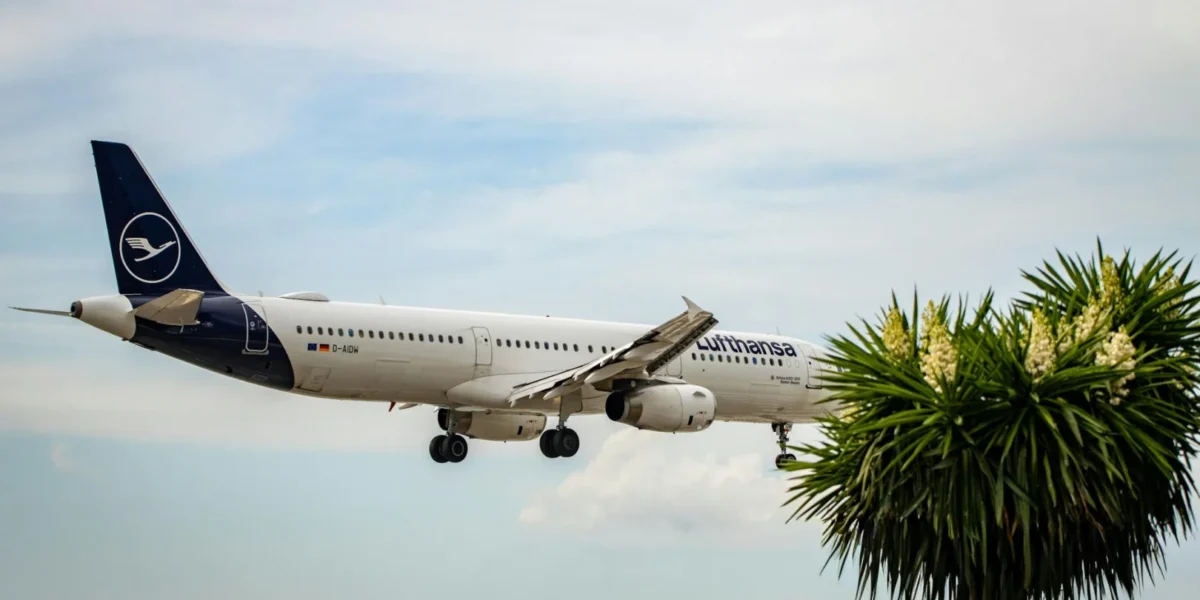 Lufthansa airplane approaching landing in Corfu, Greece with clear skies and palm trees.