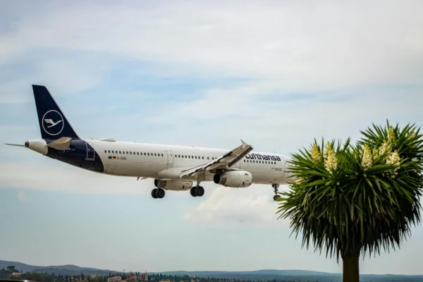 Lufthansa airplane approaching landing in Corfu, Greece with clear skies and palm trees.