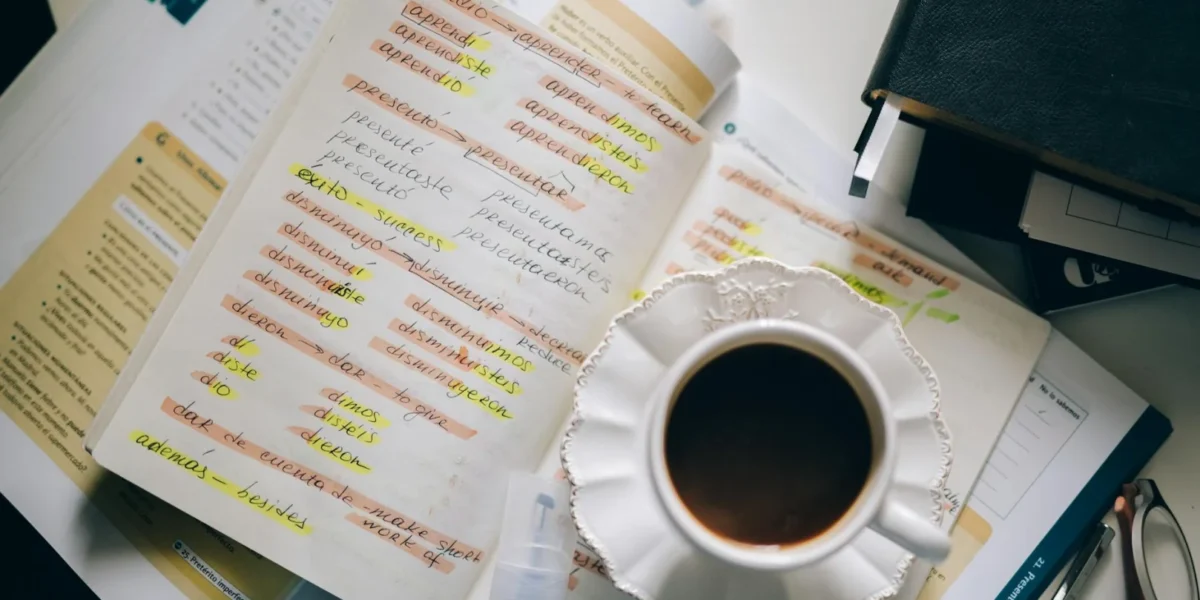 A cup of coffee on handwritten Spanish notes for language learning inspiration.
