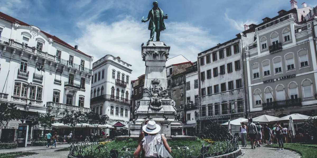 Monumental statue in a bustling Porto square, capturing local life and architecture.