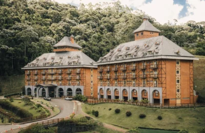 A picturesque Bavarian-style hotel surrounded by lush greenery and forest hillside.