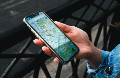 An outdoor close-up of a hand holding a smartphone displaying a map application.