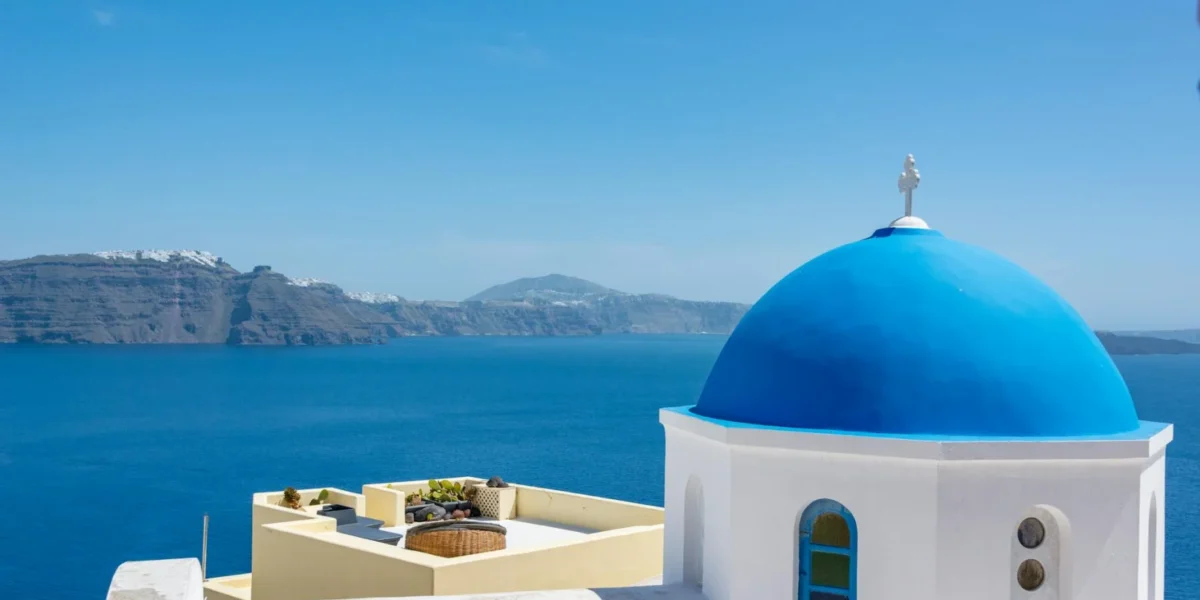 Iconic blue dome church in Santorini with a stunning view of the Aegean Sea.