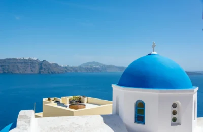 Iconic blue dome church in Santorini with a stunning view of the Aegean Sea.