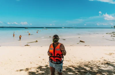 Person in snorkeling gear on a sunny beach in Krasom Subdistrict, Thailand.
