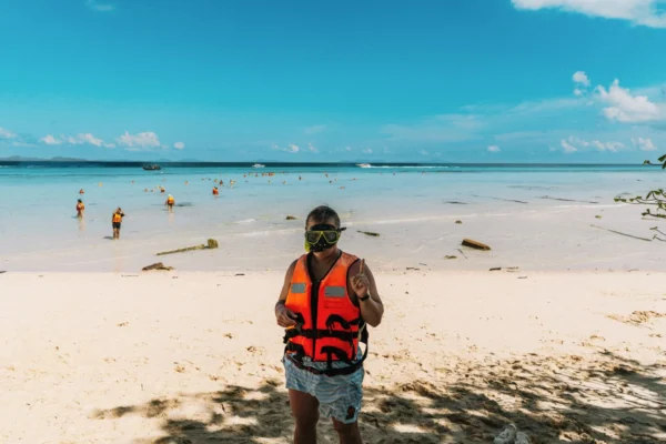 Person in snorkeling gear on a sunny beach in Krasom Subdistrict, Thailand.