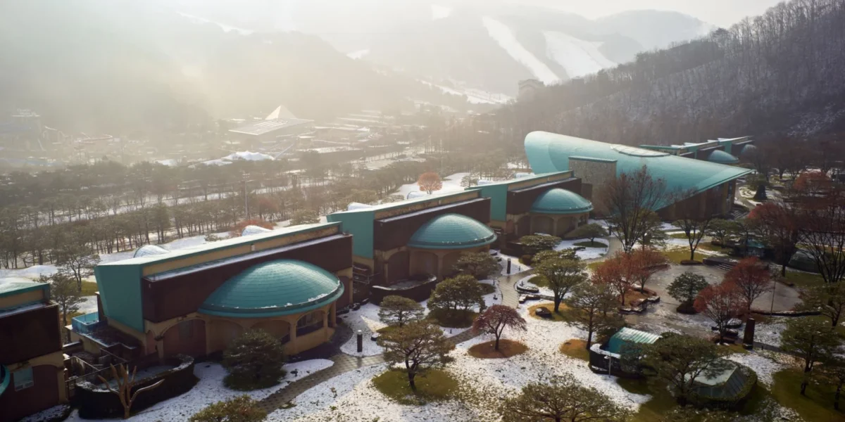 Aerial view of a scenic resort nestled in a snowy mountain setting with unique architecture.