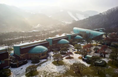 Aerial view of a scenic resort nestled in a snowy mountain setting with unique architecture.