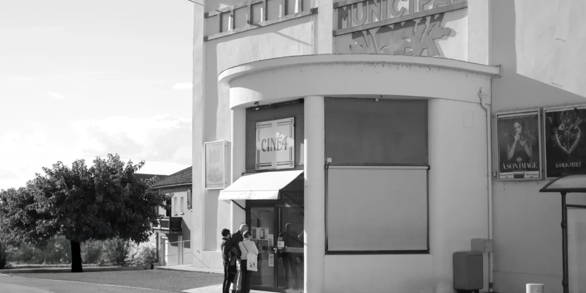 Retro theater entrance with patrons in black and white, evokes a classic cinematic feel.