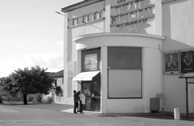 Retro theater entrance with patrons in black and white, evokes a classic cinematic feel.