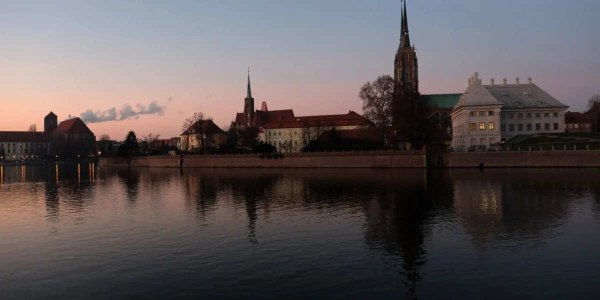 Wroclaw skyline with historic architecture reflecting on the river at twilight.