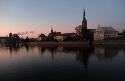 Wroclaw skyline with historic architecture reflecting on the river at twilight.