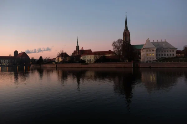Wroclaw skyline with historic architecture reflecting on the river at twilight.