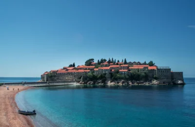 A breathtaking view of Sveti Stefan Island, Montenegro, surrounded by clear blue waters and a sandy beach.
