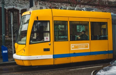 A bright yellow tram travels through the city streets, offering public transportation to passengers.