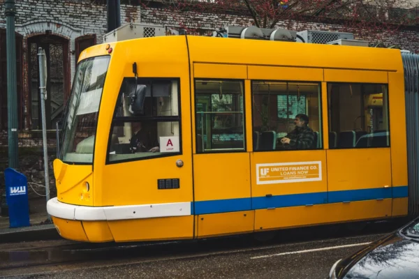 A bright yellow tram travels through the city streets, offering public transportation to passengers.