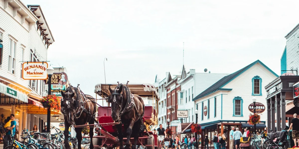 A bustling Mackinac Island street scene featuring a horse-drawn carriage and vibrant architecture.