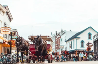 A bustling Mackinac Island street scene featuring a horse-drawn carriage and vibrant architecture.