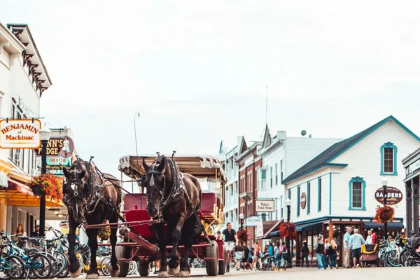 A bustling Mackinac Island street scene featuring a horse-drawn carriage and vibrant architecture.