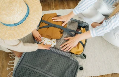 A woman and child pack clothes in a suitcase, preparing for a vacation.