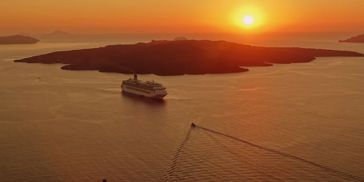 A breathtaking sunset view of a cruise ship near the island of Santorini, Greece.