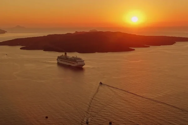A breathtaking sunset view of a cruise ship near the island of Santorini, Greece.