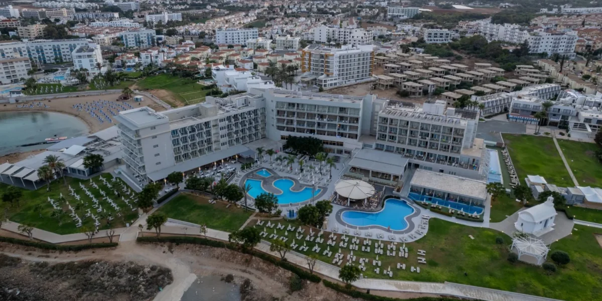 Aerial view of a luxurious resort in Pernera, Famagusta, Cyprus featuring pools and cityscape.