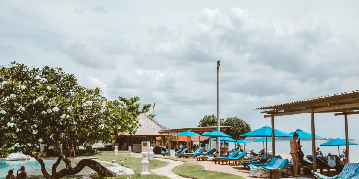 Relax at a tropical beach resort with a pristine pool, sunbeds, and ocean view.