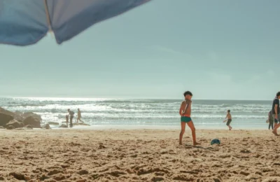 Children and adults enjoying a sunny day at a Lisbon beach, perfect for family fun.