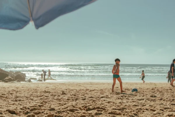 Children and adults enjoying a sunny day at a Lisbon beach, perfect for family fun.