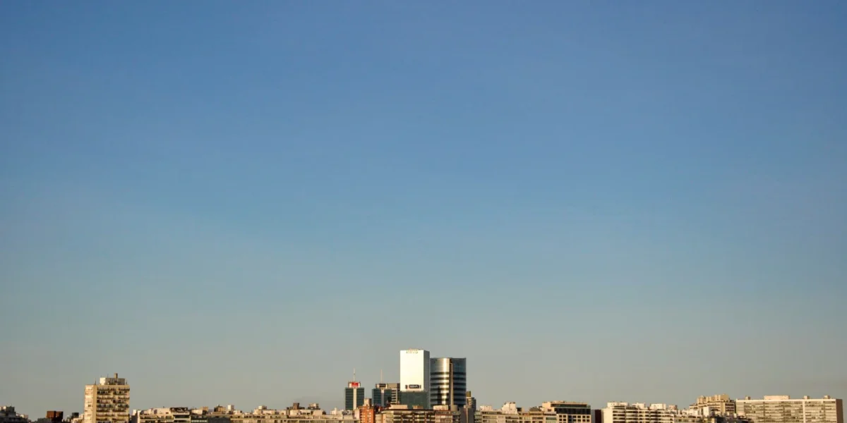 Aerial view of Montevideo's coastal skyline with clear blue sky and airplane flying above.
