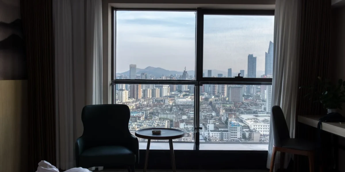 A stunning view of the city skyline from a cozy hotel room, showcasing urban architecture.