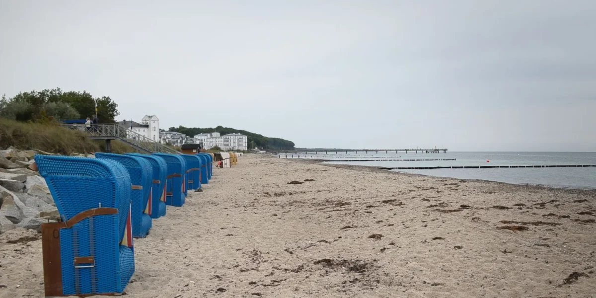 A tranquil Bad Doberan beach scene with blue Strandkorb and pier in early autumn.
