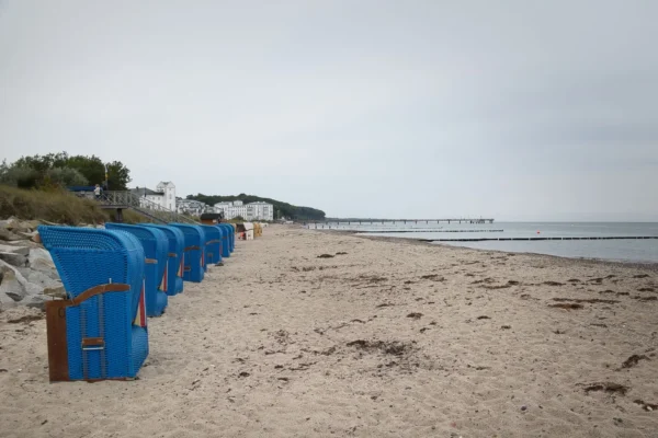 A tranquil Bad Doberan beach scene with blue Strandkorb and pier in early autumn.