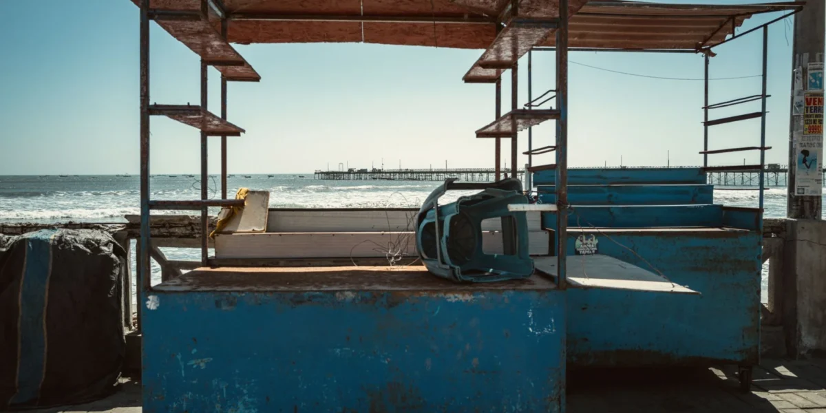 Rustic abandoned stalls on a deserted beach with ocean view, capturing solitude and decay.